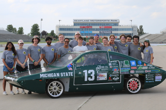 Image of MSU Solar Car racing team posing with their car.